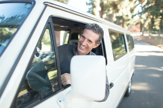 Man smiling with his head out of a car window